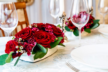 2 floral arrangements of red roses and carnations for table decoration (wedding, restaurant) on a server table, table setting