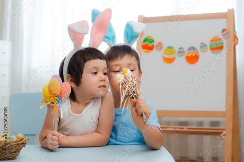 Little Boy And Girl In Bunny Ears Are Playing With Easter Eggs