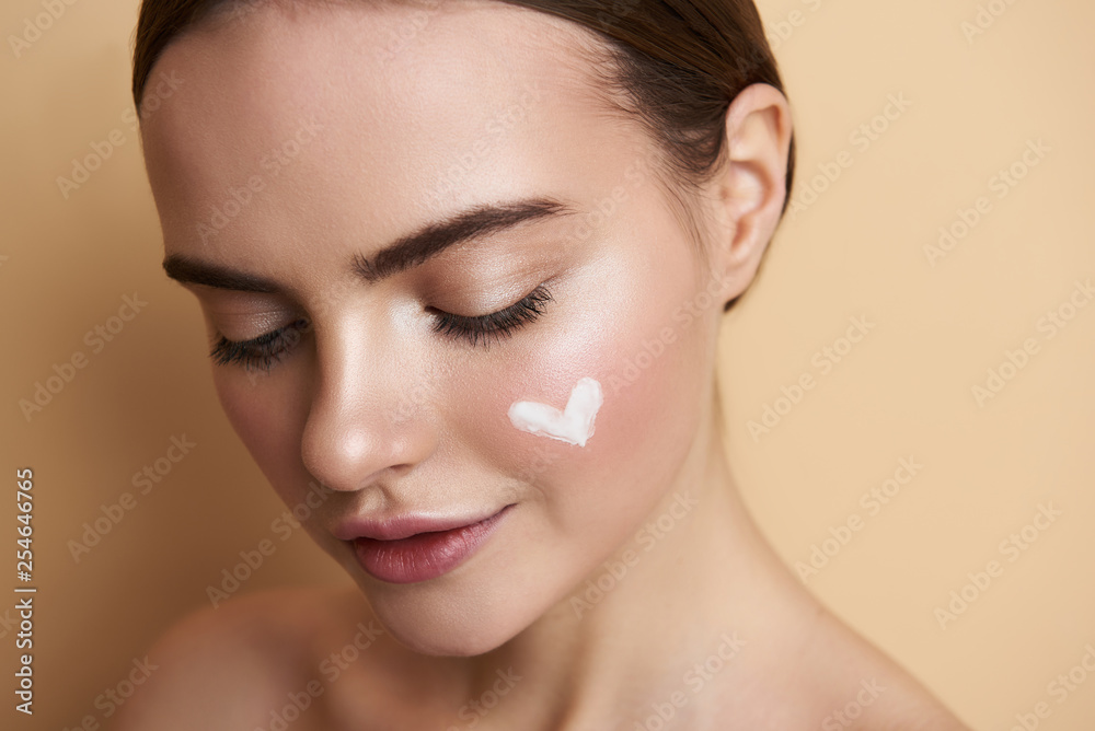 Portrait of peaceful young lady with makeup and heart picture on face - obrazy, fototapety, plakaty 