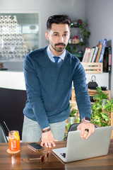 Wall Mural - Portrait of handsome young man in smart casual wear with hands over the working table and laptop in a office