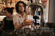 © mavoimages - Bartender mixing drinks behind a bar counter at night