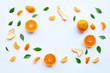 Frame of fresh orange citrus fruit with green leaves on white