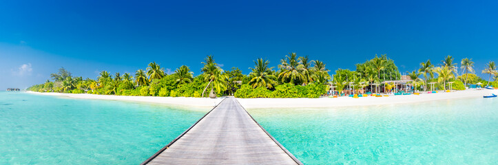 Maldives paradise scenery. Tropical landscape of palm trees and long jetty with white sandy beach. Exotic tourism destination banner