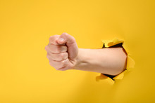 Fist Punching Through Yellow Paper