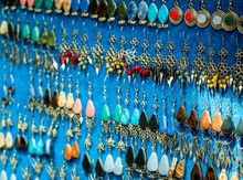 Closeup Of Different Earings Hanging On Blue Fabric Showcase