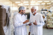 © Dusan Petkovic - Supervisor talking to worker while holding tablet. Both dressed in uniforms. Food factory interior.
