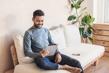 Handsome young man using digital tablet at home. Student men resting t in his room. Home work or study, freelance concept