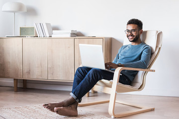 Wall Mural - Handsome young man using laptop computer at home. Student men resting  in his room. Home work or study, freelance concept