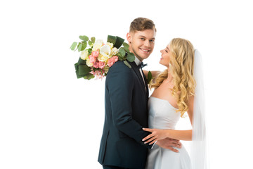 Wall Mural - happy bride with wedding bouquet hugging smiling groom isolated on white