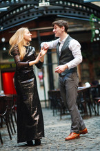 Joyful Young Couple In Love Dancing Latin On Evening Street Near The Cafe Of Old Town