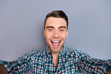 Close up photo attractive amazing macho he him his man arm hand telephone smart phone make take selfies mouth open wearing casual plaid checkered shirt outfit isolated grey background