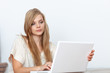 © gallofilm - Young woman using a notebook computer indoors