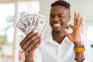 Canvas Print - African american man holding fifty dollars bank notes doing ok sign with fingers, excellent symbol