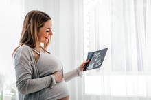 Pregnant Woman At Home Looking Her Baby On Ultrasound Image, Usg Photo
