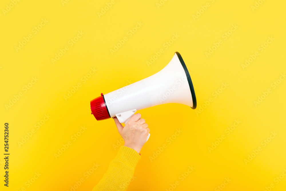 megaphone in hand on a yellow background, attention concept announcement - obrazy, fototapety, plakaty 