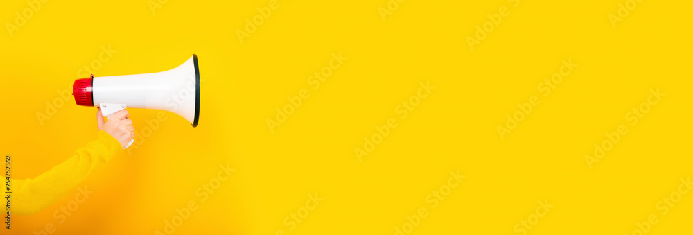megaphone in hand on a yellow background, panoramic image, attention concept announcement - obrazy, fototapety, plakaty 