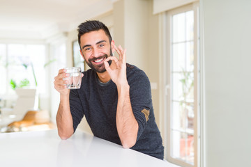 Poster - Handsome hispanic man drinking a fresh glass of water doing ok sign with fingers, excellent symbol