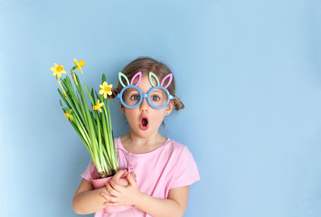 cute little child wearing bunny ears glasses and holding flowers on easter day. easter girl portrait