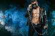 © Mike Orlov - Men fashion. Close-up portrait of a brutal and fit man topless in a leather jacket with chains. Athlete bodybuilder on black background.