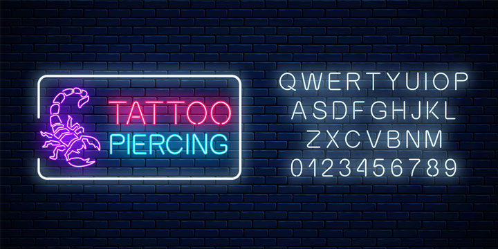 Tattoo and piercing parlor glowing neon signboard with scorpio emblem and alphabet. Tattooing salon sign