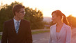CLOSE UP: Cheerful man and woman in formal clothes walk to work at sunrise.