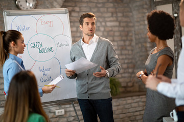 Businessman communicating with his team while giving presentation in the office.