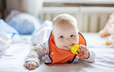 Wall Mural - Cute baby eating fruit in nibbler on bed at home