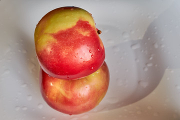 two red ripe juicy apples are lying one on the other on a white plate. fruits and vegetables. vitamin c. energy of nature