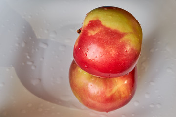 two red bright juicy ripe apples lie one on another on a white plate. fruits and vegetables. vitamin c. energy of nature