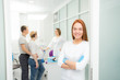 © Dmitry - Young beautiful woman doctor stands against the background of patients in the clinic. Patients married couple, woman pregnant