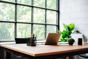 Image of an homeoffice interior with wood desk work. Computers and office supplies with no employees .