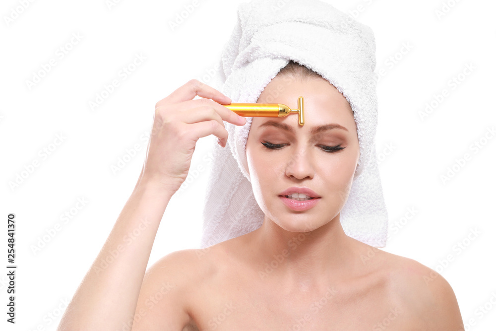 Young woman with facial massage tool on white background