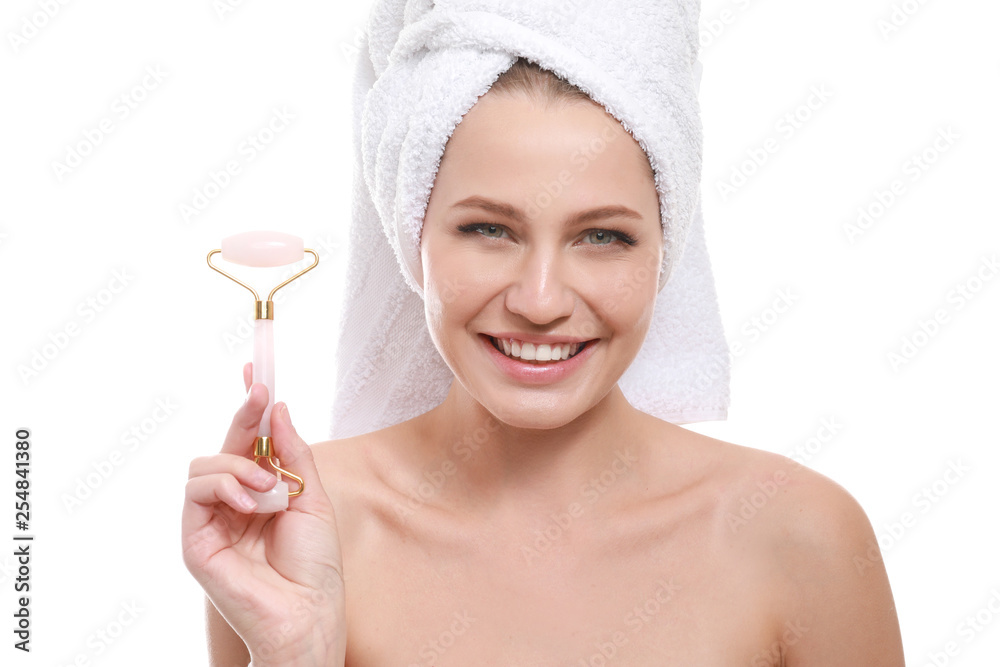 Young woman with facial massage tool on white background
