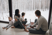 Family At Home In Pajamas. Daughter And Son. Wake Up In The Morning. Hugging And Kissing, Looking Out The Window. Beautiful Winter Outside The Window. Large Windows To Floor. Nice View From Window.
