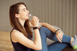 © Viktoria - Sporty girl with dark hair holds a plastic bottle with clean water in her hands is sitting on a gray chair resting after a workout a healthy diet, a healthy lifestyle