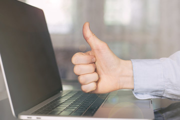 Hand of man pose finger thumb up (like) with laptop