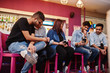 © AS Photo Family - Group of stylish asian friends wear on jeans sitting at chairs against bar in club and looks at mobile phones.