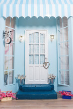 Spring Photo Zone. White Door. Metal Lamps On The Wall. Blue Steps. Glazed Windows With Flowers. Interior Photo Studio. Flowers In Metal Buckets. Blue Wall.