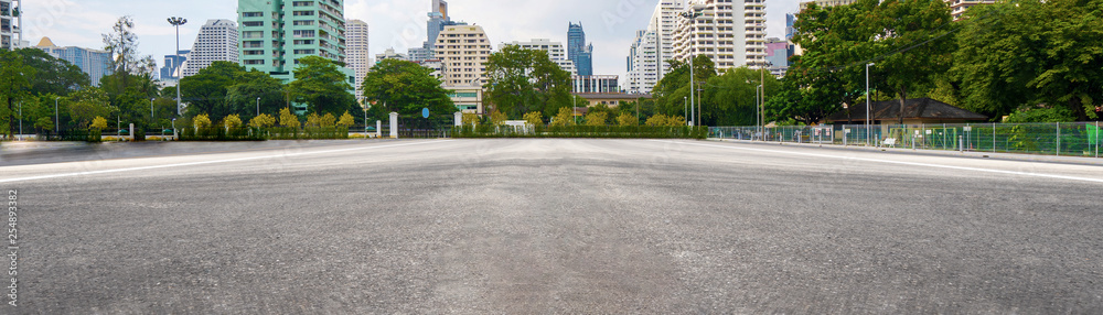 Empty asphalt road with city in the background - obrazy, fototapety, plakaty 