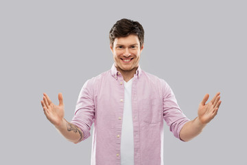 Wall Mural - people concept - smiling young man showing size of something over grey background