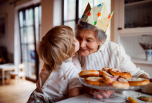 Senior Grandmother With Small Toddler Boy Making Cakes At Home, Kissing.