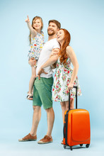 Happy Surprised Parent With Daughter And Suitcase At Studio Isolated On Blue Background. Travel, Vacation, Parenthood, Togetherness, Tourism Concept.