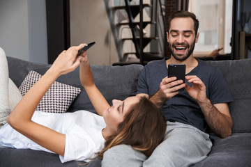 Wall Mural - Cheerful young couple relaxing on couch at home