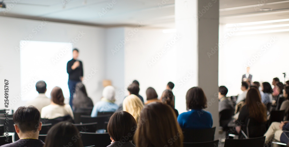 "Speaker on Stage at Conference Meeting Event. Presenter at Business Seminar Photo. Audience Watching a Manager Presentation. Blurred Image of Lecturer Presenting To Audience During Speech. " - obrazy, fototapety, plakaty 