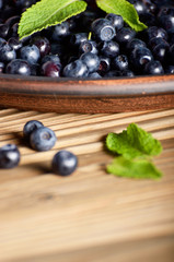 Wall Mural - Clay plate full of Ripe organic blueberries on wooden table