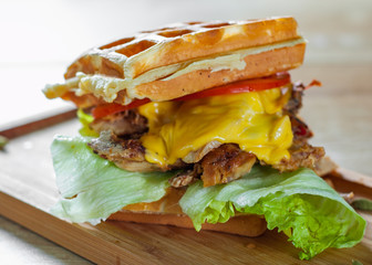 Waffle sandwich with meat, cheese, sauce and vegetables on wooden table background