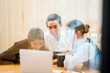© Danon - A diverse team of businesspeople sit around a laptop for a business discussion and is having a hot beverage (hot chocolate or coffee) in a meeting room in the office. Image taken with blur foreground.