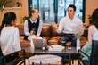 © Danon - A group of professionals discussing work inside the office. They are wearing elegant corporate attire while sitting on a brown couch.