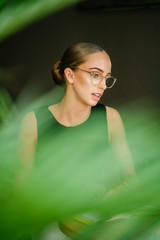 Wall Mural - A beautiful and confident Caucasian businesswoman sitting at a table in a meeting room and having a discussion with a person that is out of view. Image taken with blur foreground. 