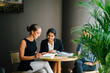 © Danon - A young Indian Asian woman is having a business meeting with her team in a meeting room. She is smiling as she talks to her colleagues. They are all professionally dressed.